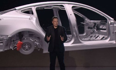 Tesla's founder Elon Musk stands in front of a rendering of the company's Model 3 body-in-white. It's been speculated that Tesla's first mass-market car will use a mixed-material construction.