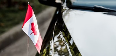 selective focus of canadian flag with maple leaf on black car