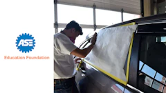 Automotive technician preparing vehicle for paint repair in professional workshop
