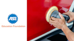 Automotive technician polishing red car panel with orbital buffer