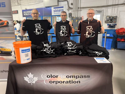 Color Compass team showcasing branded t-shirts at corporate event with charity donation bucket