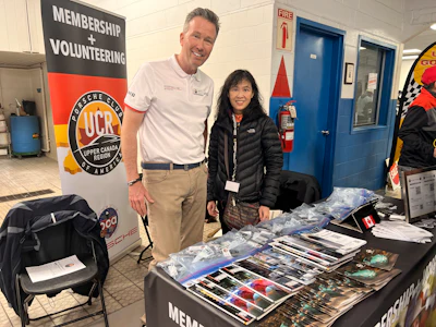 Porsche Club UCR membership booth with volunteers showcasing club materials