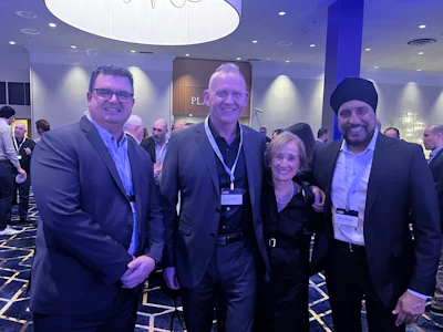 Four professionals networking at corporate conference in elegant blue-toned event space