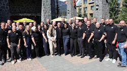 Corporate team group photo at mountain location with stone buildings and yellow umbrellas