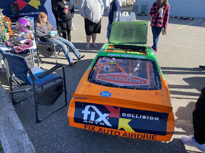 Race car with Fix Auto Airdrie branding at outdoor promotional event