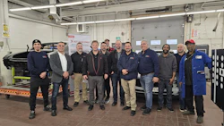 Team of automotive technicians posing in professional workshop with diagnostic equipment