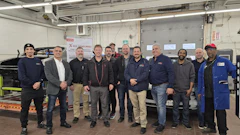 Automotive technician team posing in workshop with diagnostic equipment