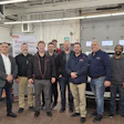 Automotive technician team posing in workshop with diagnostic equipment
