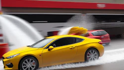 Yellow sports car speeding on wet road, creating dramatic water splash