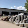 Metal warehouse with stacked tires and parked vehicles on a sunny day