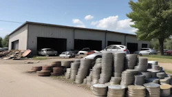Metal warehouse with stacked tires and parked vehicles on a sunny day