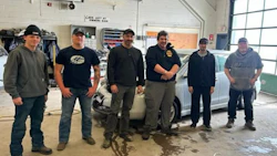 Auto repair team of six workers standing together in garage workshop