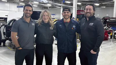 Automotive service team posing together in professional workshop with vehicles