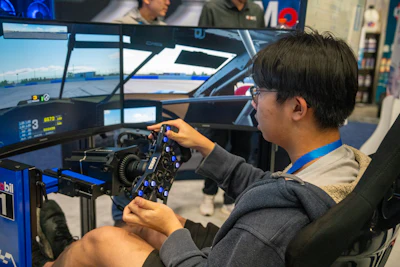 Racing simulator with multi-screen setup and driver using professional steering wheel