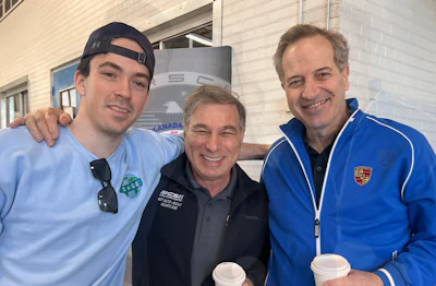 Three smiling men in casual sportswear posing together outdoors with coffee