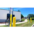 Electric vehicle charging station with yellow Aviva charging pillars on a sunny day