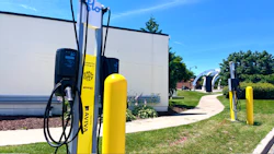 Electric vehicle charging station with yellow Aviva charging pillars on a sunny day