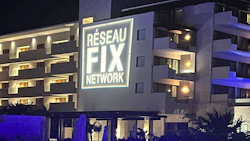 Modern building at night with Réseau Fix Network illuminated logo on white facade