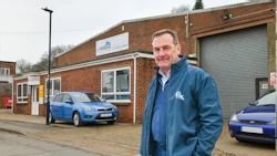 Professional at automotive business with blue Ford vehicles and brick building