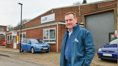 Professional at automotive business with blue Ford vehicles and brick building