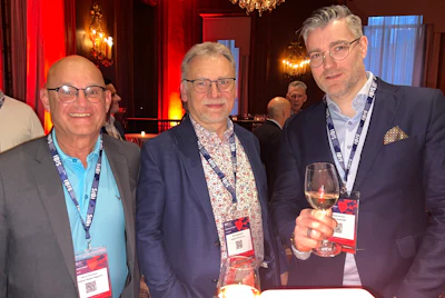 Three professionals networking at conference with red ambient lighting
