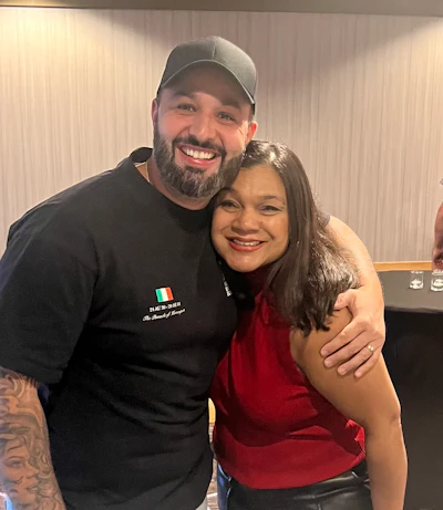 Smiling friends embracing, one in black cap and shirt, another in red top