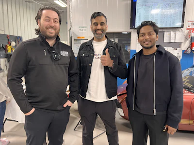 Automotive repair team in black jackets posing together in workshop