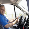 Smiling delivery driver in blue shirt seated in commercial van