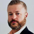 Professional businessman in dark suit with beard looking directly at camera