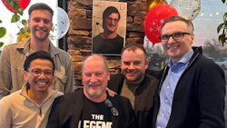 Smiling team of five men celebrating together with festive balloons