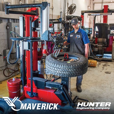 Technician operating Maverick tire changing machine in automotive workshop