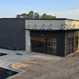 New commercial metal building with glass entrance and parking area under blue sky