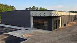New commercial metal building with glass entrance and parking area under blue sky