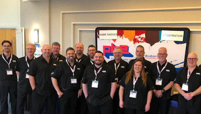 PBE Distributors team photo with employees in matching black uniforms at corporate event