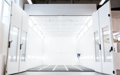 Empty white industrial spray painting booth with metal flooring and bright illumination