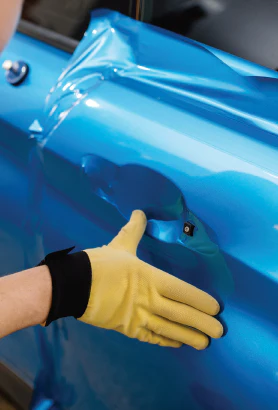 Yellow-gloved hand touching glossy blue industrial surface