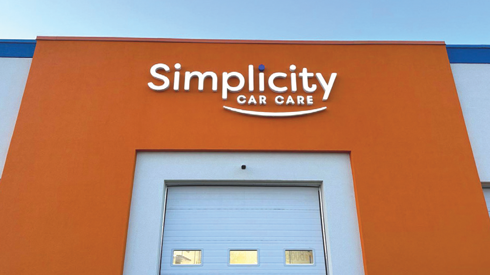 Simplicity Car Care facility with orange exterior and blue garage door