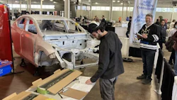 Auto body repair technician working on damaged vehicle frame at skills competition
