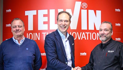 Telwin corporate team celebrating partnership with handshake against red innovation backdrop