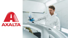 Technician applying automotive paint using spray equipment in professional refinishing workshop
