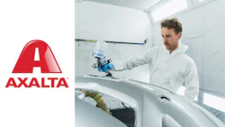 Technician applying automotive paint using spray equipment in professional refinishing workshop