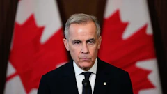 Canadian official speaking at podium with national flags in background
