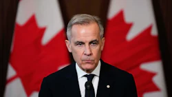 Canadian official speaking at podium with national flags in background