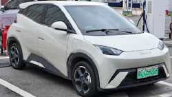 White electric compact SUV at charging station with green license plate