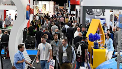 Busy automotive and technology trade show with diverse professionals networking between exhibition booths