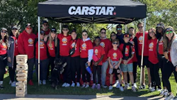 CARSTAR team in red shirts posing together at outdoor community event