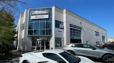 Preston Collision auto repair shop with white building and parked vehicles