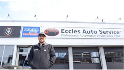 Automotive technician at Eccles Auto Service storefront, wearing dark jacket and cap
