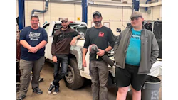 Auto repair team of four technicians standing together in service garage workspace