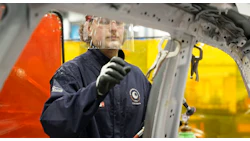 Technician in safety gear working on industrial machinery with yellow and orange backdrop